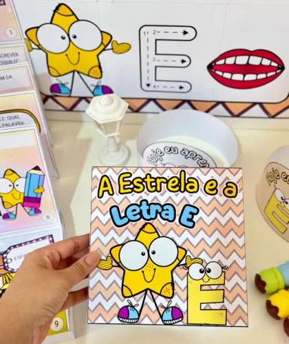 Mão segurando capa do material A Estrela e a Letra E colorida
